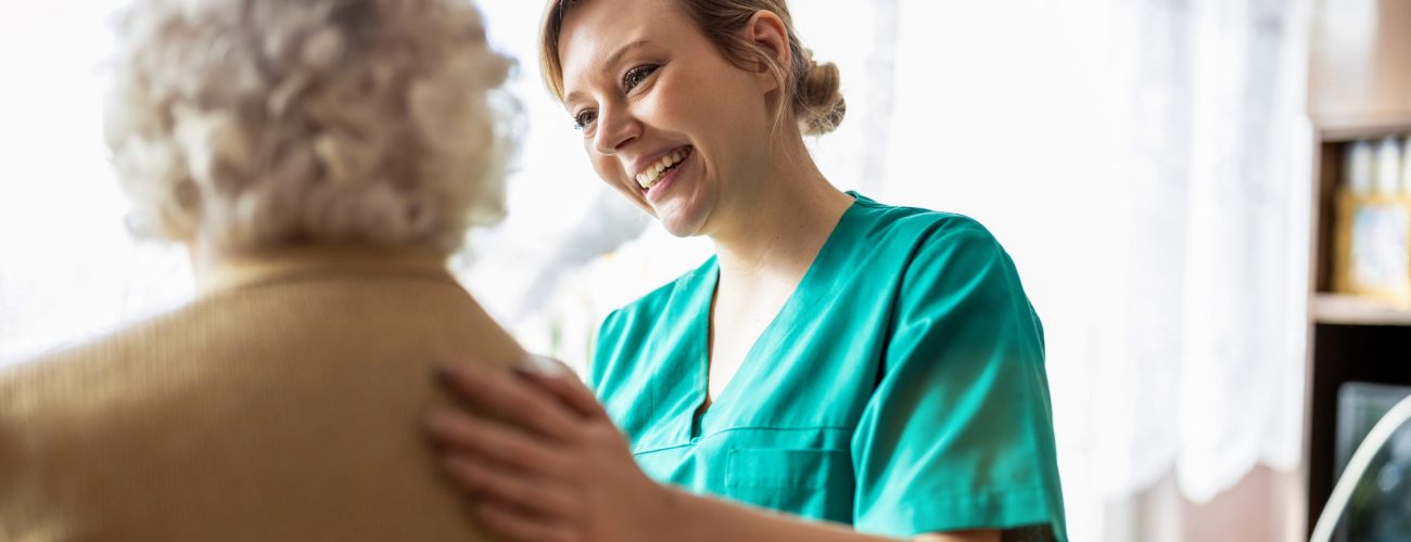 A friendly nurse supporting a senior lady at home.